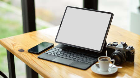Modern equipments concept, Modern digital tablet computer blank screen mockup with smartphone, camera and coffee cup on table.の写真素材