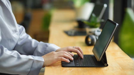 Side view, business woman working on portable tablet computer, typing her works on tablet.の写真素材