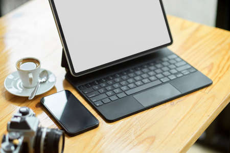 Close-up freelancer or photographer portable workplace concept, tablet mockup, mobile phone, and vintage camera on tableの写真素材