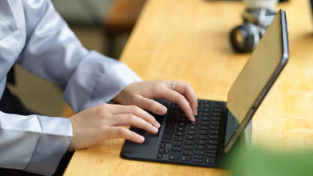 Cropped shot female assistant, businesswoman working on digital tablet computer, typing on portable keyboard.の写真素材