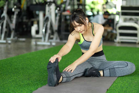 Woman in a comfy sport wear stretching her legs and arms after had a hard exercise at the gym.の写真素材