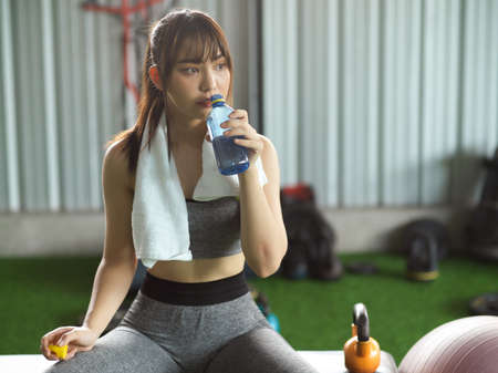 Attractive young fitness woman resting and drinking water after sport workout at the gym.の写真素材