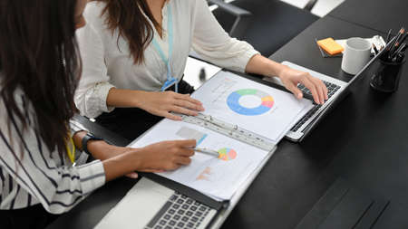 Cropped image of two successful and smart businesswomen in a financial team working and analysing on business data together.の写真素材