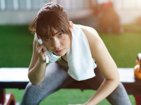 Portrait of Active fitness woman sits on a chair with hand towel on her shoulder, resting after body weight training.の写真素材