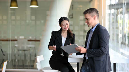 Female accountant explain accounting plans on digital tablet computer to her executive male...