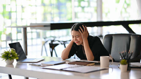 Business woman feeling shocked and stressed after reading business sale performance, get a unsatisfied email from customer, get a fired contract from her boss.の写真素材