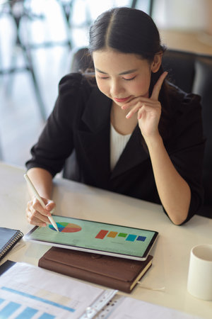 Female accountant working and making pie chart graphic report via modern tablet computer at her deskの写真素材