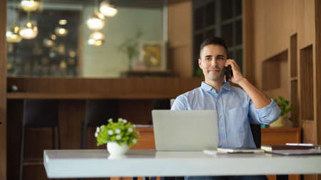 Handsome millennial businessman on the phone with executive manager at head quarter, business tele negotiation.の写真素材