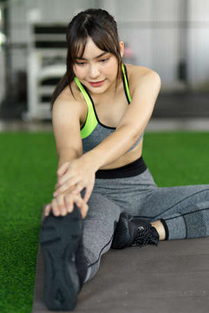 Sport and recreation concept. Woman in sportswear doing legs stretching to ready for exercise bodyweight training.の写真素材