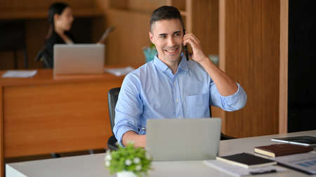 Handsome caucasian businessman investment broker, insurance realtor on the phone call with client at office.の写真素材