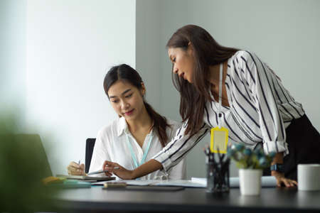 Attractive asian female manager at the office training and explaining project details to her team.の写真素材