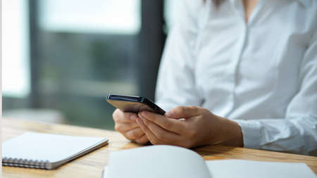 Close-up, Female assistant using smartphone, reading and answering the business email.の写真素材