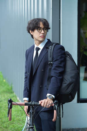 Portrait of Businessman with curly hair in formal suit going to work by bike. urban commuting.の写真素材