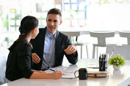 Caucasian businessman manager talking with his female marketing campaign manager in the office.の写真素材