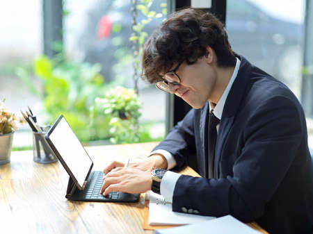 Successful businessman in digital tech company working on his digital tablet computer in the office.の写真素材