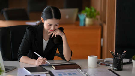 Happy asian female entrepreneur concentrated on her business project plans. businesswoman in office.の写真素材