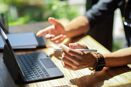 Close-up Businessman hands holding stylus pen and working on digital tablet computer at his desk.の写真素材