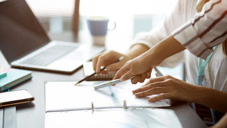 Cropped image of Two businesswomen discuss and voting business strategy plan for the next project. pen pointing on papersの写真素材