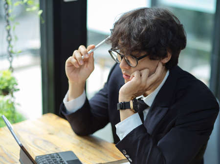 Tired male employee working on tablet computer and thinking creative ideas for business strategy.の写真素材