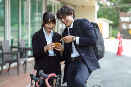 Happy businessman and female worker enjoy talking while looking on the mobile phone at the street.の写真素材