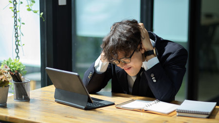 Failed businessman upset with his sale performance. Tired male worker works on tablet computer.の写真素材