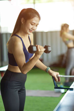 Portrait of attractive asian fitness lady in sportswear exercise lifting dumbbell in fitness club.の写真素材