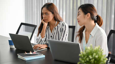 Two of asian female managers in the meeting, listen to her staff presenting new online strategy.の写真素材