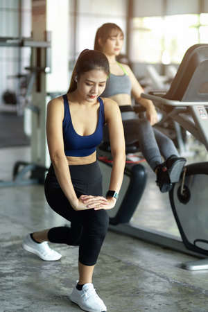 Gorgeous woman trains, stretchs her legs and warming up before doing exercise as the gym centre.の写真素材