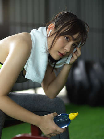 Portrait of beautiful athletic fitness girl feeling exhausted, dehydrated and needs to rest after intensive fitness workout.の写真素材
