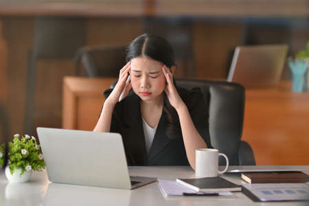 Thoughtful young asian businesswoman pensive thinking her new project at her working desk in office.の写真素材