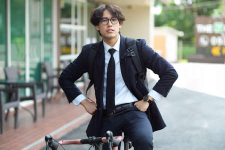 Urban businessman rides his bike to work. Eco-friendly transportation. Man in business suit on bike.の写真素材