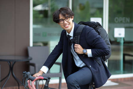 Businessman in formal suit commuting to work by bicycle. Young salary man ride bicycle to work.の写真素材