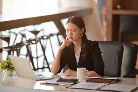 Businesswoman confused with her assistant's financial work on laptop computer. thoughtful, pensive.の写真素材