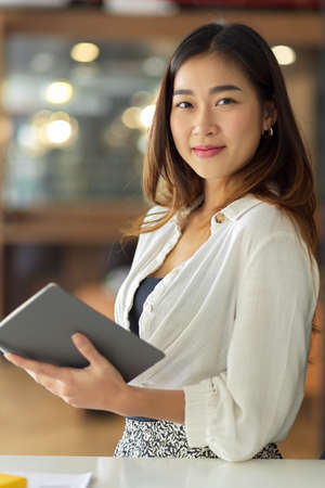 Portrait of Beautiful professional businesswoman holding touchpad, standing in modern office.の写真素材