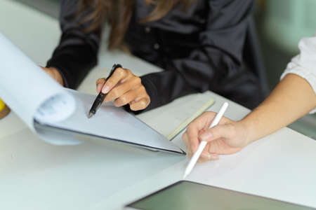 Cropped image of business team working together, checking the informations on report and using tablet computer.の写真素材