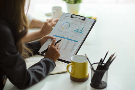 Close-up businesswoman reviewing business data chart report of company financial team in the office.の写真素材