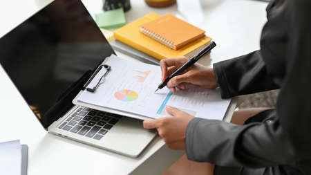 Cropped image of female executive checking financial statement on the data chart report at her desk.の写真素材