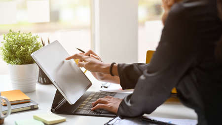 Cropped image of elegant business woman in black dress working on digital tablet computer in office.の写真素材