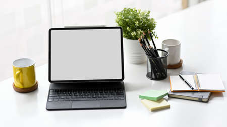 Digital tablet computer blank screen with keyboard mockup with office supplies on working desk.