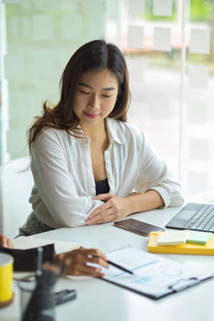 Portrait of young beautiful executive female in the meeting, listen her staff explain new strategy plans for new product.の写真素材