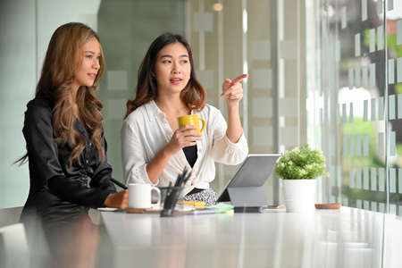 Two female business colleague friends were talking, chatting, and having a conversation in coffee break.の写真素材
