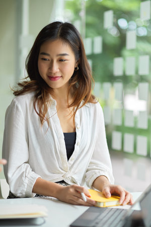 A young female entrepreneur in the meeting, looking at her company's product on the desk in the board room.の写真素材