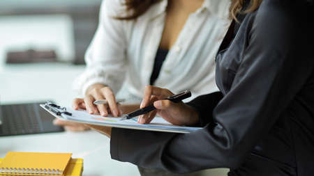 Female boss reviewing and providing feedback on her assistant's work. Women in business collaborating.の写真素材