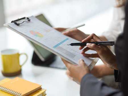 Cropped image of female manager looking at financial report paper on the clipboard.の写真素材