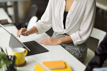 Female freelancer using digital tablet computer, drawing something on touchpad, sitting in co working space.の写真素材