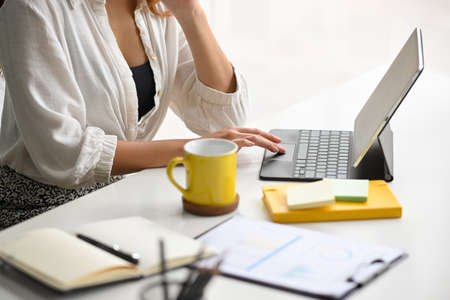 Cropped, closeup shot of a businesswoman using a modern portable tablet computer to do her assignment.の写真素材
