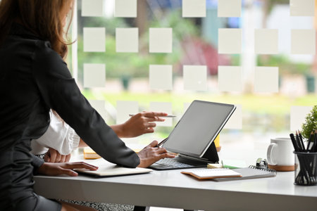 Elegant businesswoman in black dress analyse financial data on company's database via portable tablet computer.の写真素材