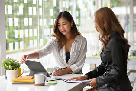 Two of female in business financial consultant are meeting and analysing on online report via tablet in office.の写真素材