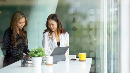 Two asian business female worker sitting in office room and working on the project together.の写真素材