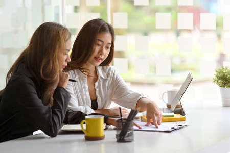 Concentrated asian young businesswoman coworkers look at report paperwork together at meeting.の写真素材